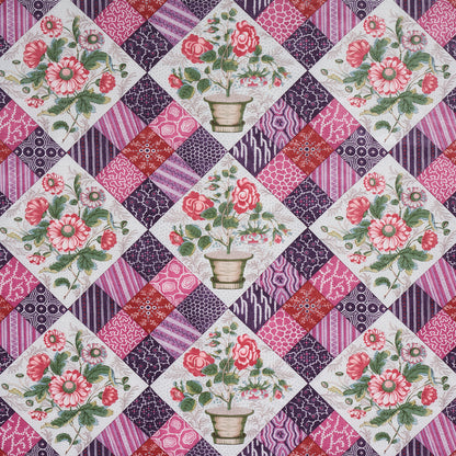 Quilted patchwork fabric with floral diamond panels showing pink roses in pots, framed by purple and magenta patterned squares.