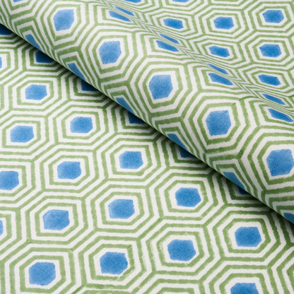 Green hexagonal lattice pattern with blue centers on a light background, folded cotton fabric.