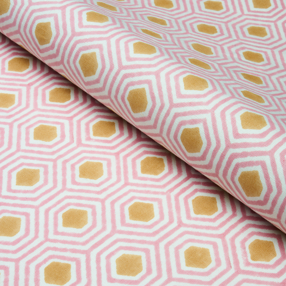Pink and white geometric hex pattern fabric with mustard-yellow centers, rolled textile.