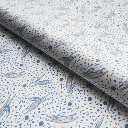 White fabric with a pale blue rabbit print and tiny dot motifs; airy cottage-style textile.