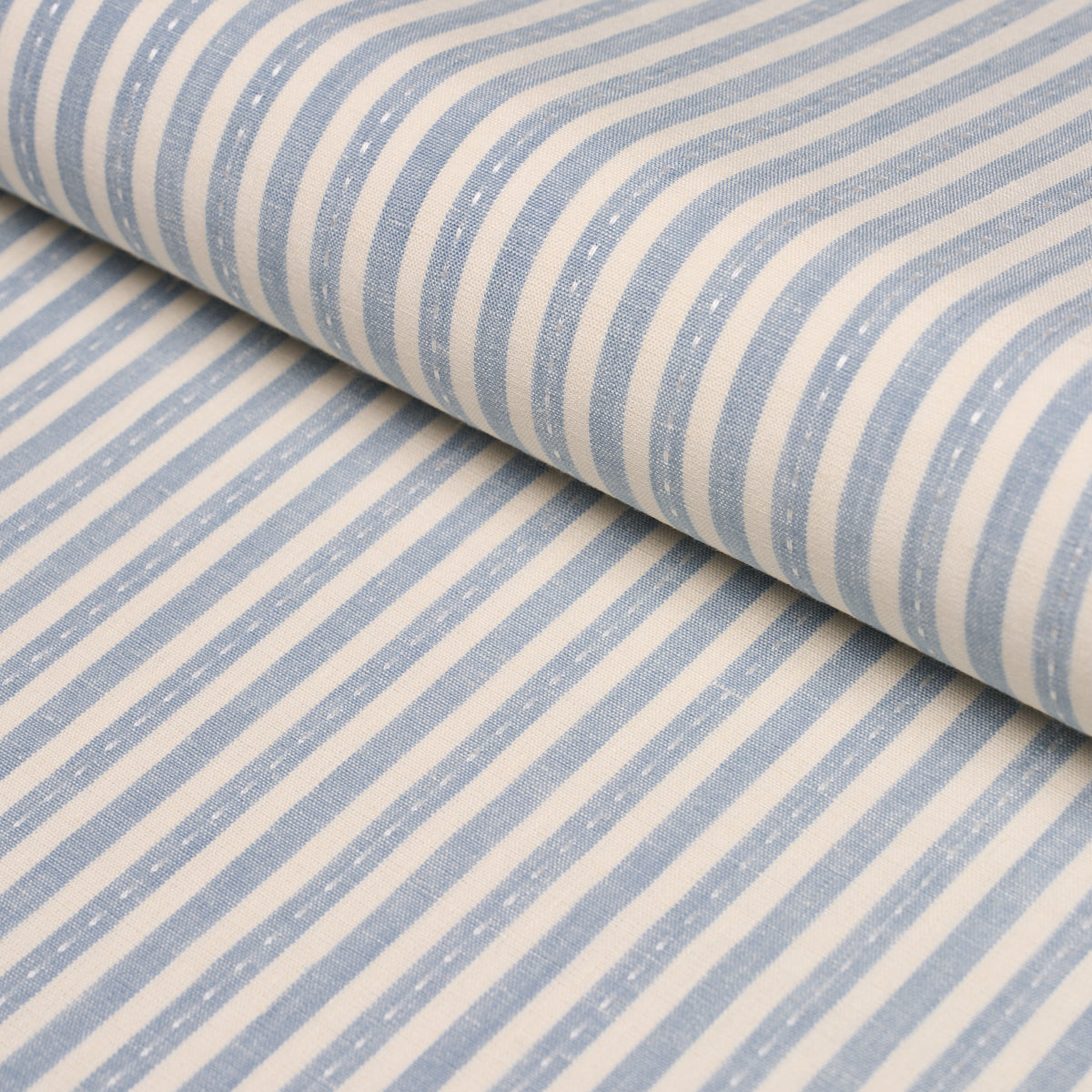 Soft blue and white striped cotton fabric, rolled up, nautical casual textile.