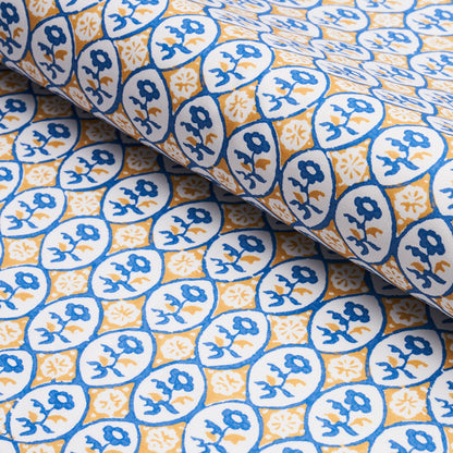 Blue and yellow azulejo-inspired tile print cotton fabric, circular floral medallions, folded.