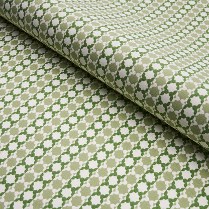 Beige woven fabric with a green geometric lattice/trellis pattern; rolled fabric sample for upholstery or drapery.