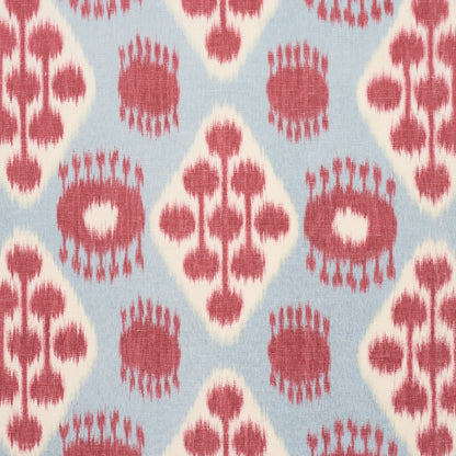 Blue woven fabric with pink-red ikat-inspired diamonds and circular motifs; boho textile for cushions or curtains.