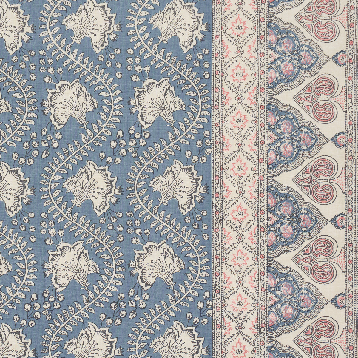 Blue field rug with white scrolling floral vines; cream-pink border with delicate motifs and arches.