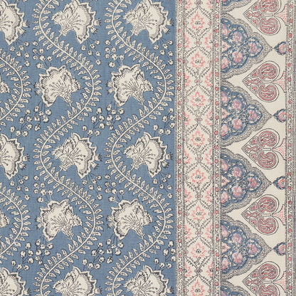 Blue field rug with white scrolling floral vines; cream-pink border with delicate motifs and arches.