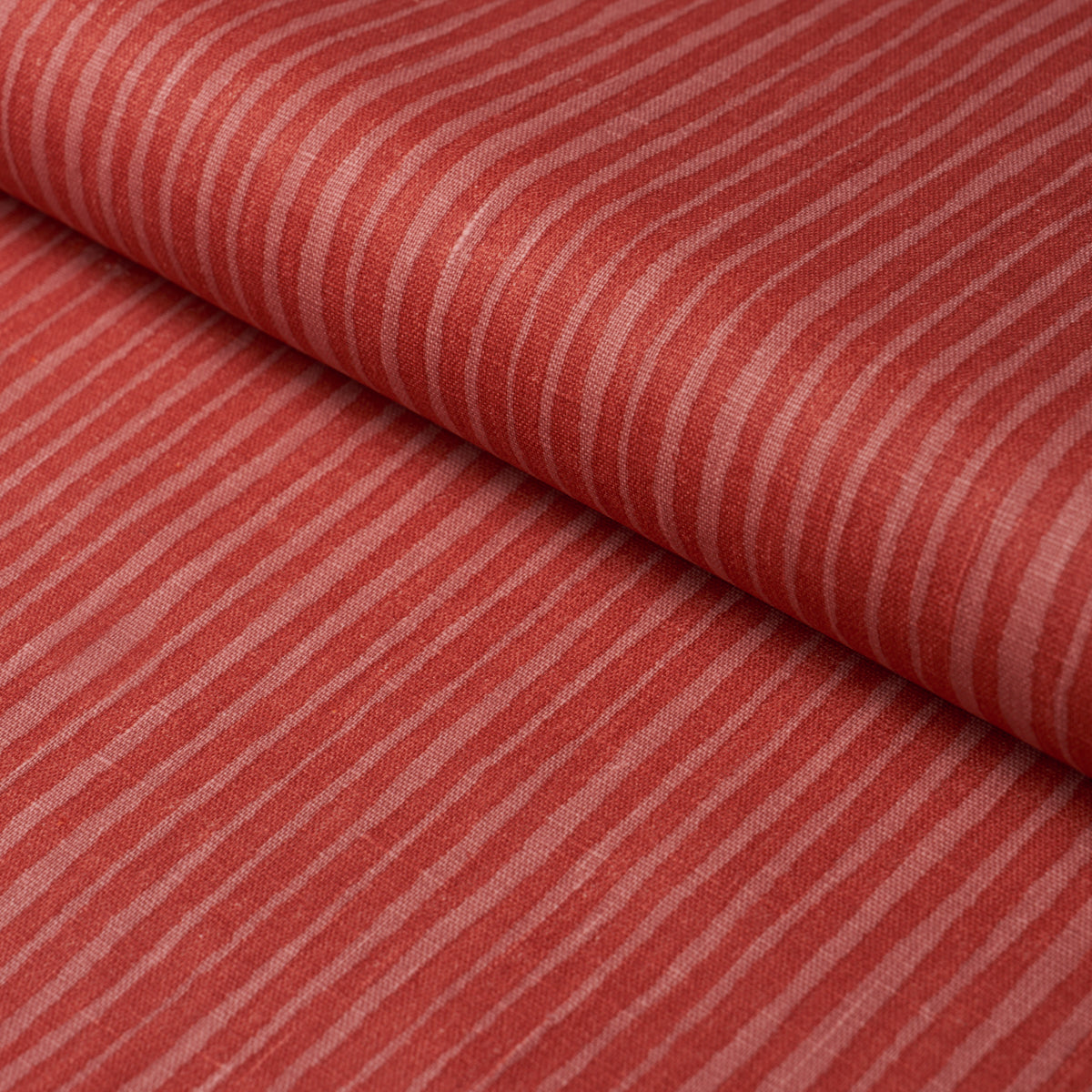 Red striped fabric with cream narrow stripes, folded; soft cotton textile for apparel or home decor.