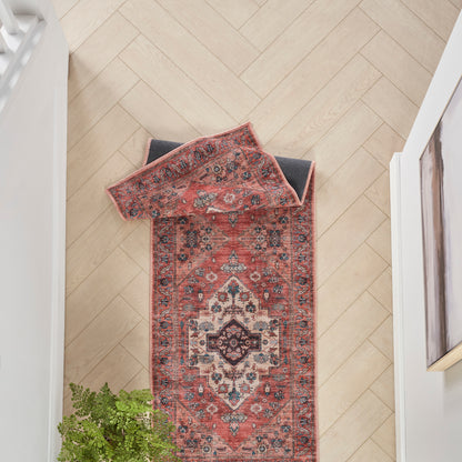 Persian-style red runner rug with central medallion and intricate borders on a light wood herringbone hallway floor.