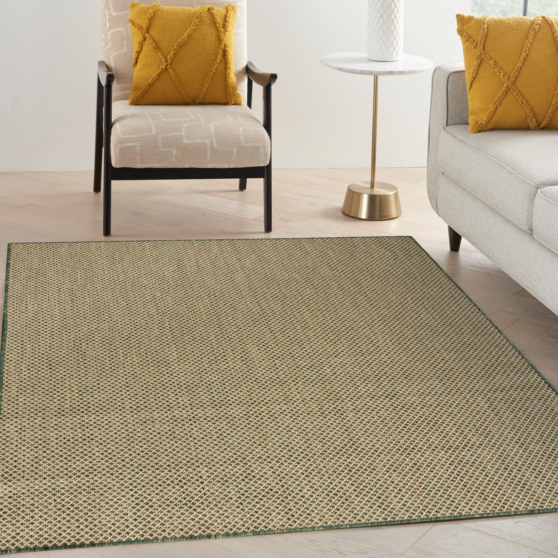 Beige woven area rug with green edge in a contemporary living room; mustard throw pillows on beige chair and gray sofa.