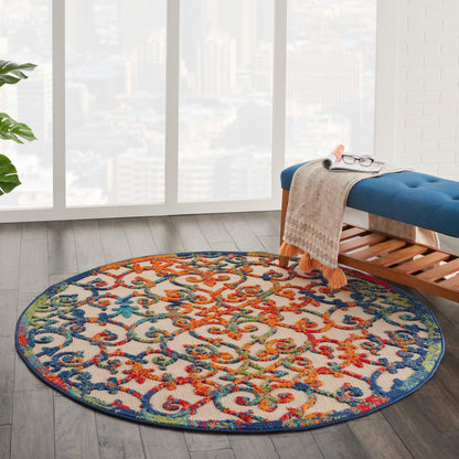 Round area rug with vibrant multicolor floral scroll pattern in red, blue, green and orange on a light background.