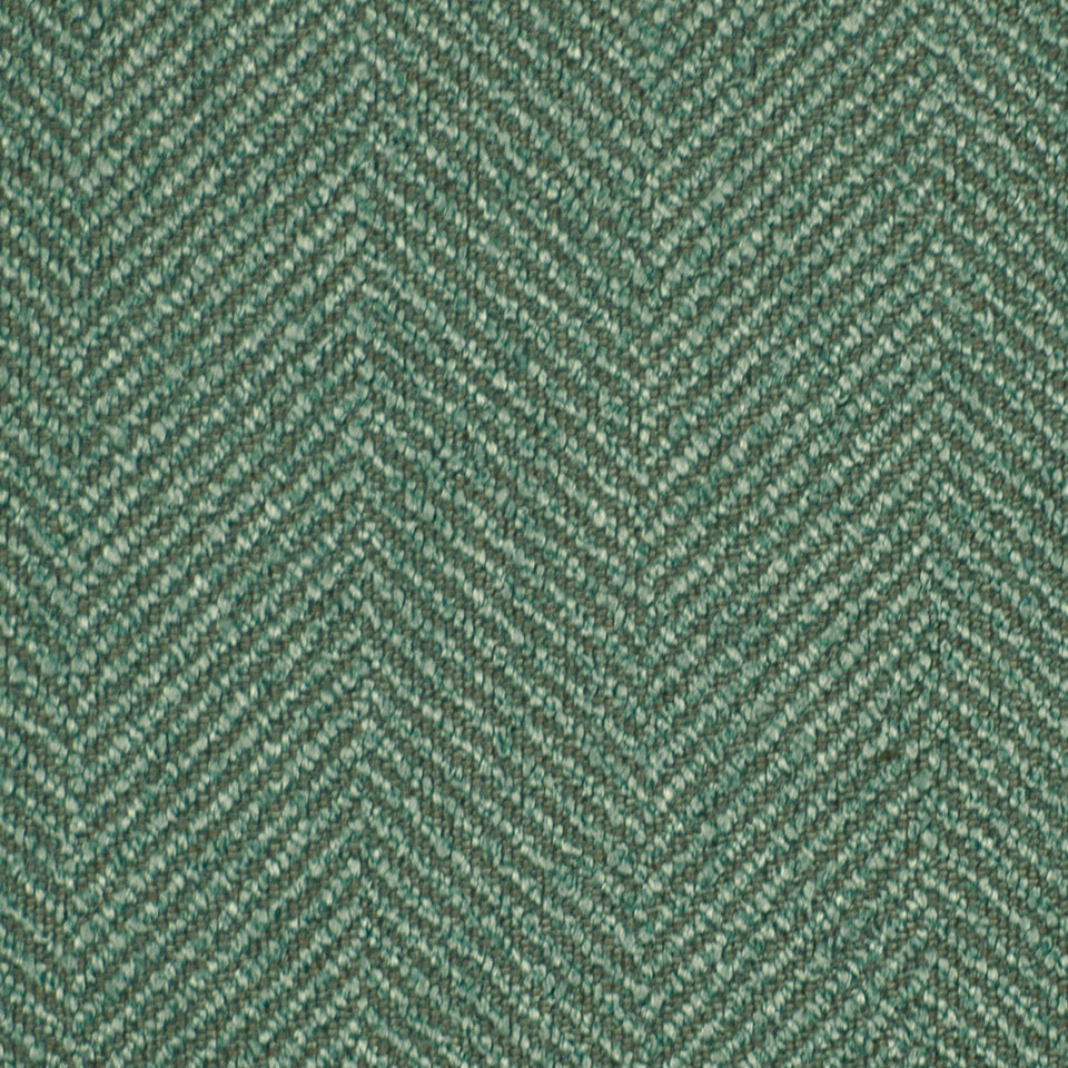 Close-up of green herringbone tweed fabric with chevron weave and wool-like fibers