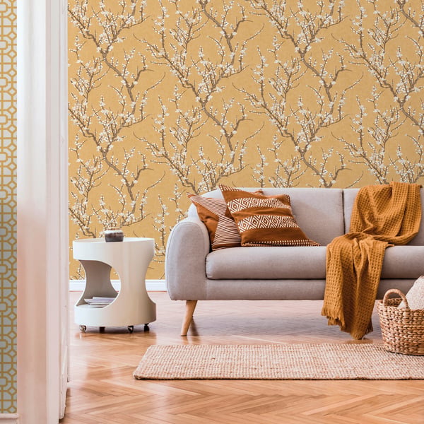 Mustard yellow botanical wallpaper in living room with gray fabric sofa, orange throw, white modern side table, jute rug.