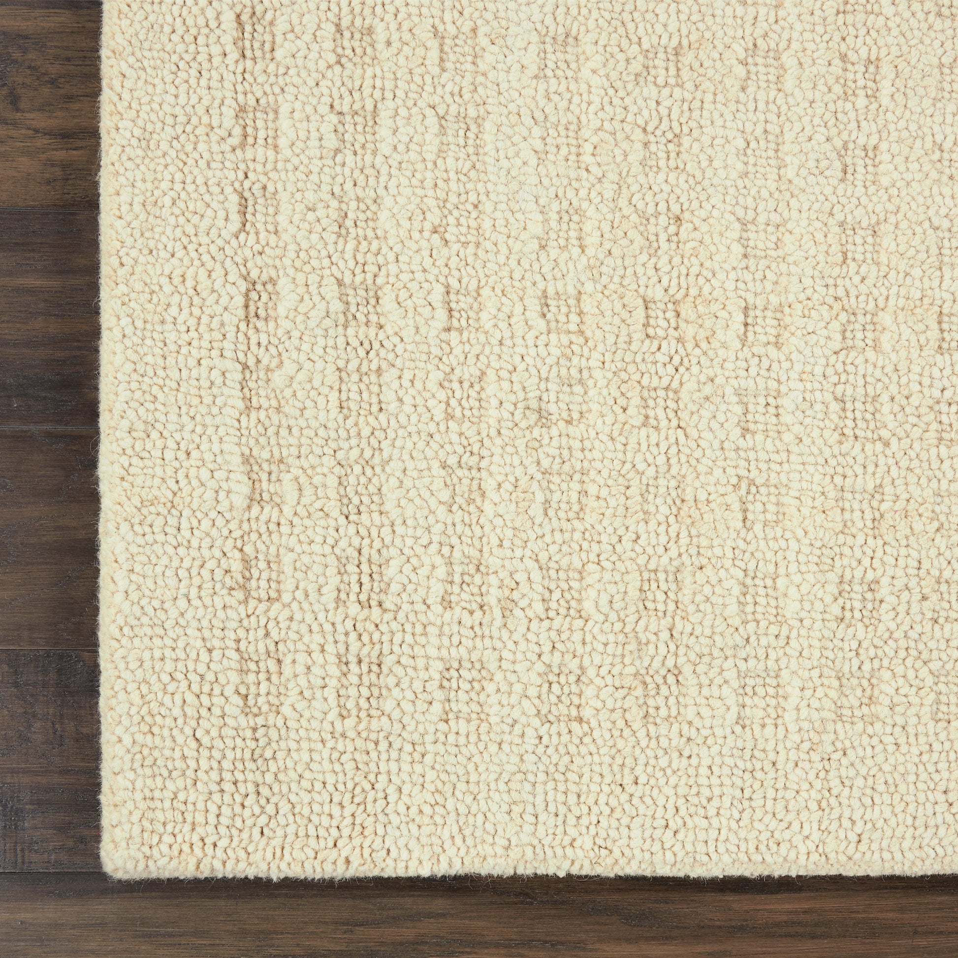 Cream boucle textured shag rug on dark wood floor.