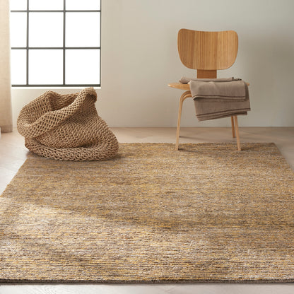 Natural jute rug on light wood floor with curved wooden chair, gray throw, and chunky beige knitted pouf.