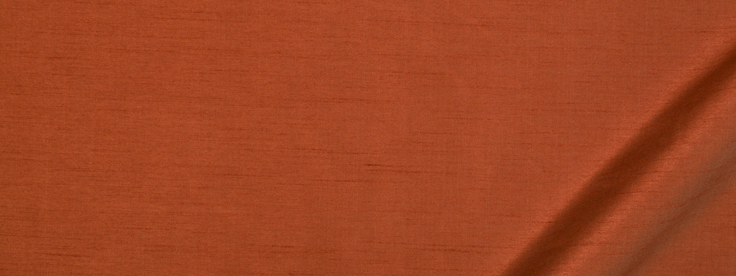 Close-up of burnt-orange fabric with visible weave and soft crease.