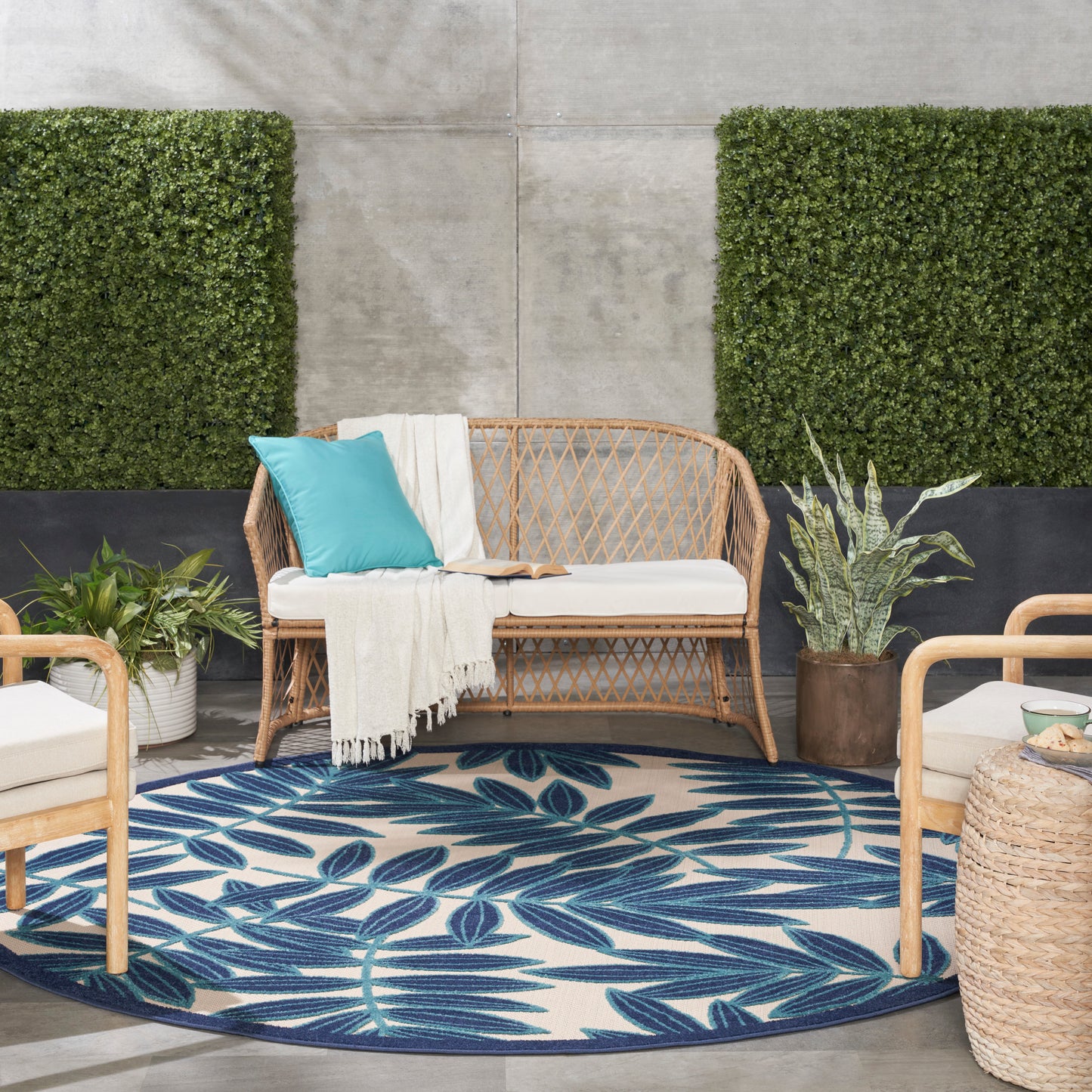Round tropical rug with blue leaf pattern; potted plants nearby