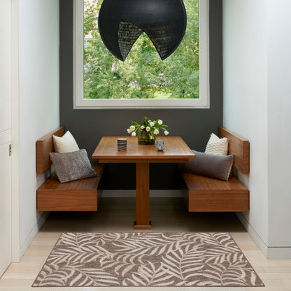 Walnut corner dining nook & square pedestal table, leaf-pattern rug, white cushions, vase of white flowers, dark wall.