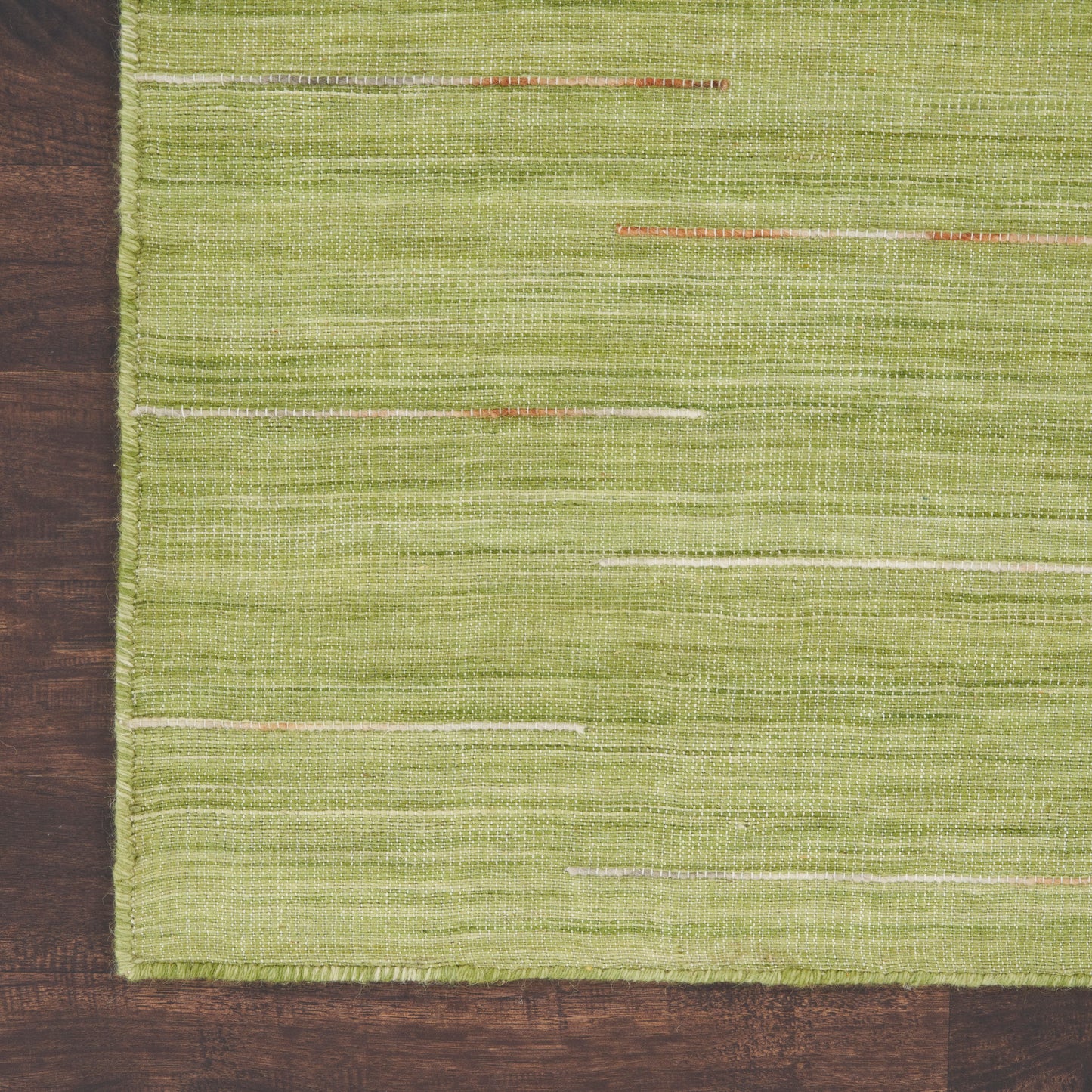 Olive-green woven rug with thin cream & pale orange horizontal stripes on a dark wooden floor.