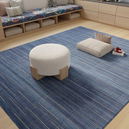 Blue striped woven area rug with light blue accents; round white textured ottoman with wooden legs and beige floor cushions