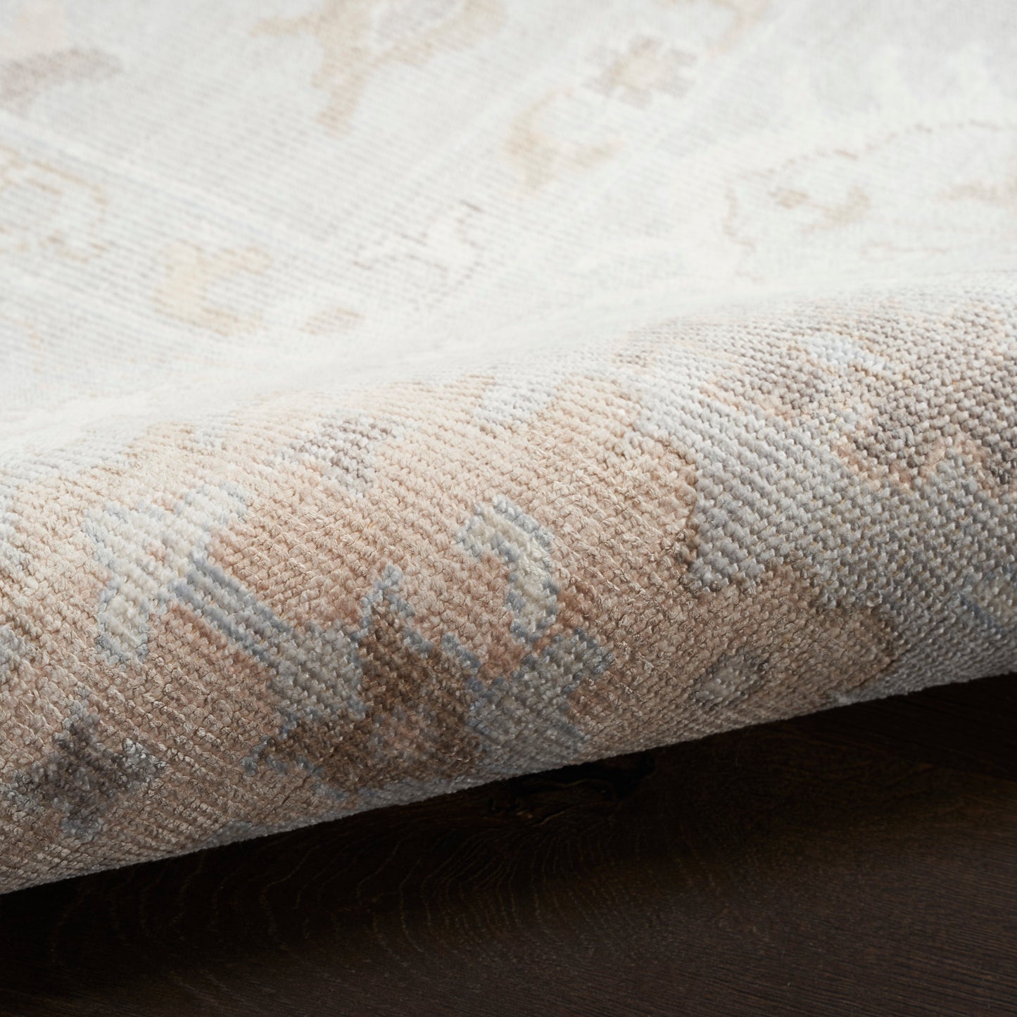 Beige and cream oriental-style rug with pale blue accents, woven texture and folded edge.