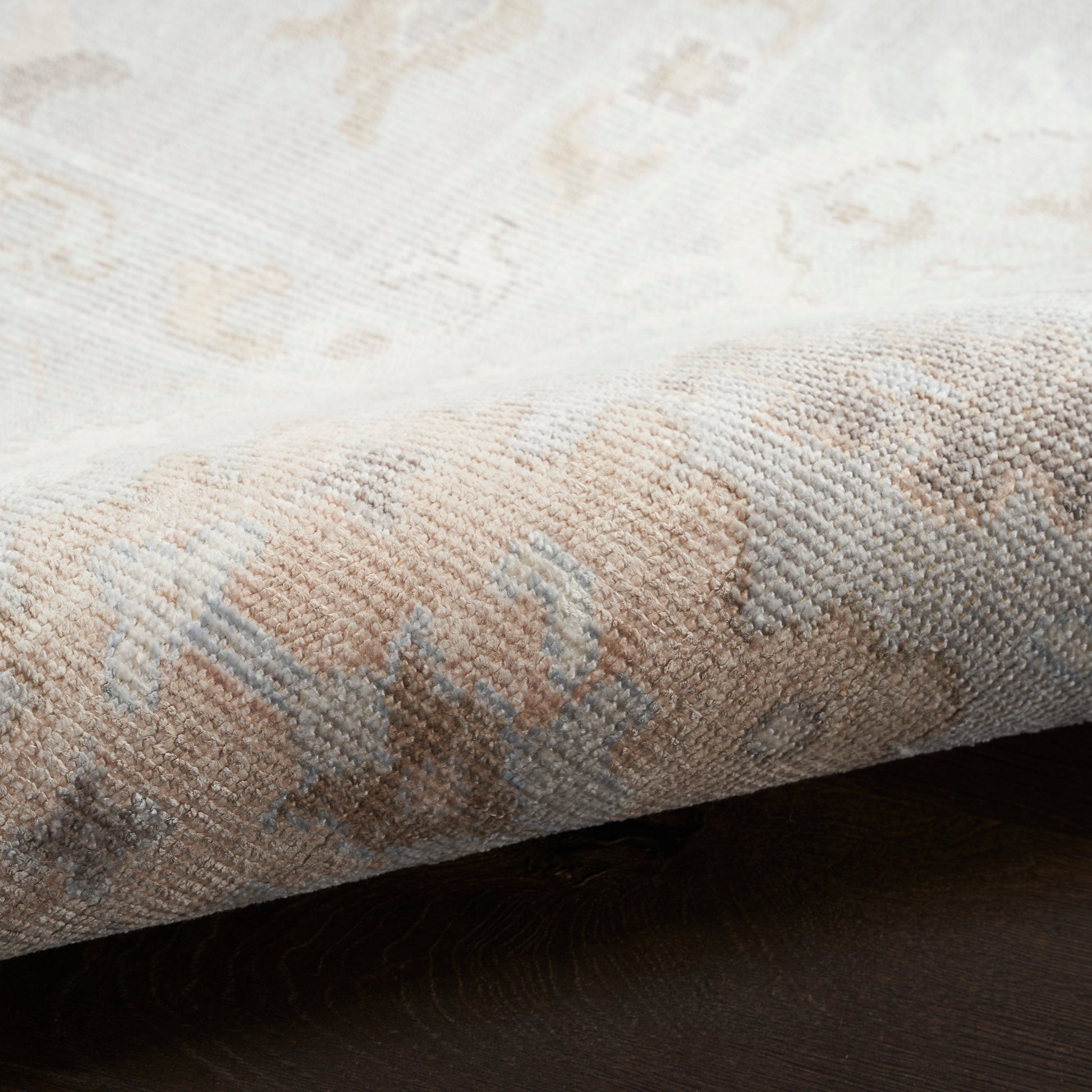 Beige and cream oriental-style rug with pale blue accents, woven texture and folded edge.