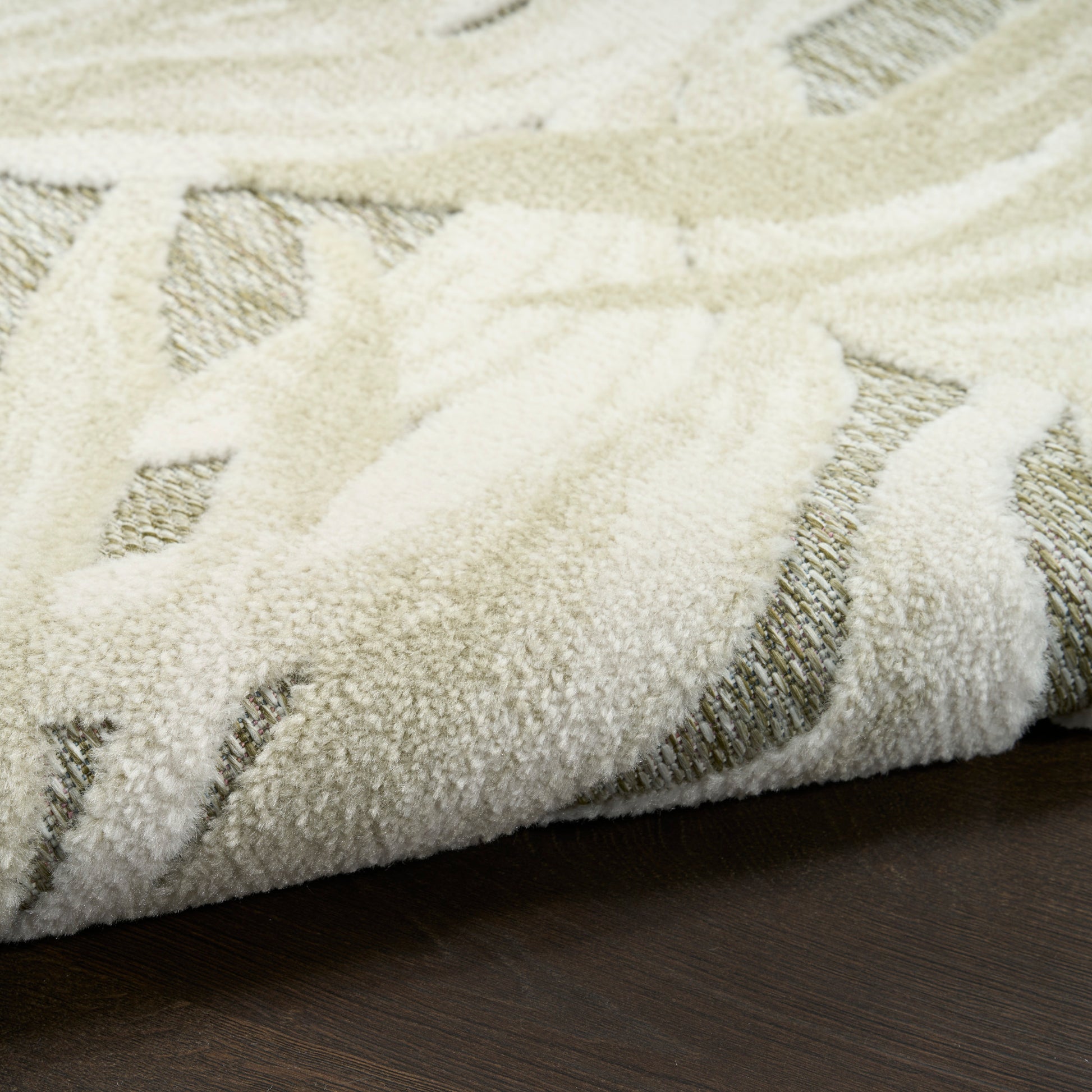 Cream textured area rug with beige geometric pattern, rolled edge on dark wood floor.