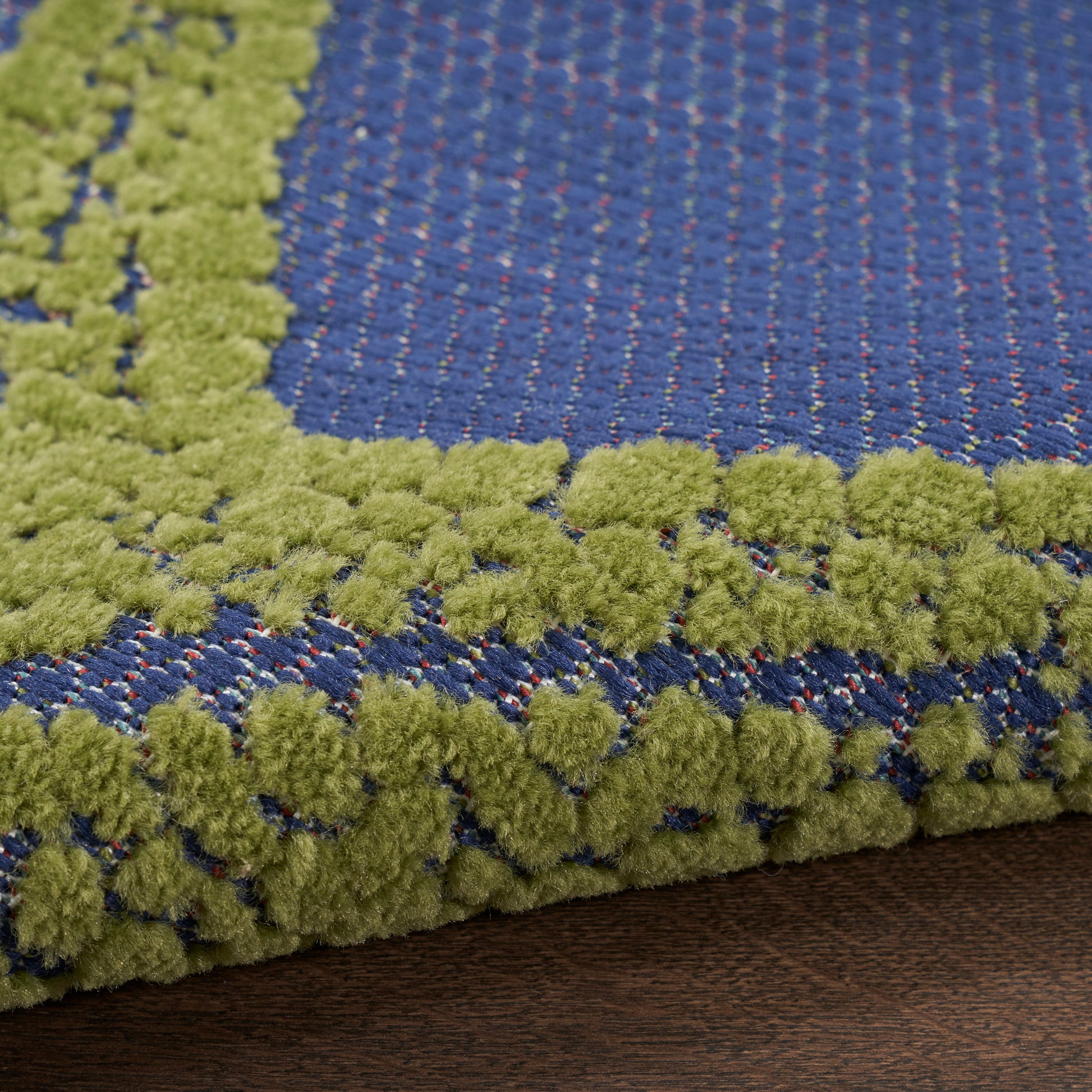 Blue woven rug with lime green boucle fringe border; textured, modern geometric rug.