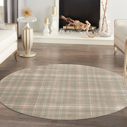 Round plaid rug in soft greens & beige with pink accents; cozy living room with wood floor & neutral furniture.