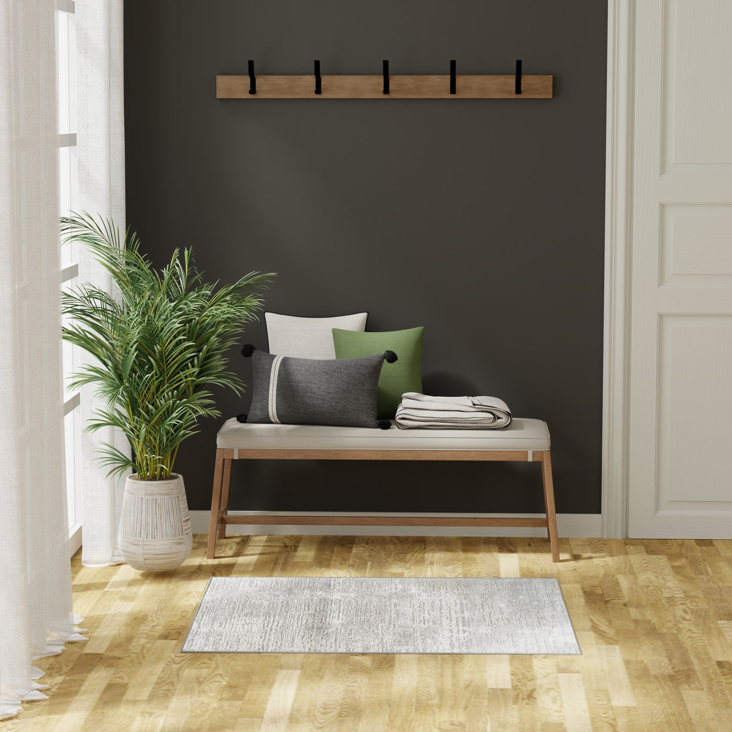 Contemporary entryway with dark accent wall, wooden bench, beige cushions, green pillows, coat rack, plant, light rug.