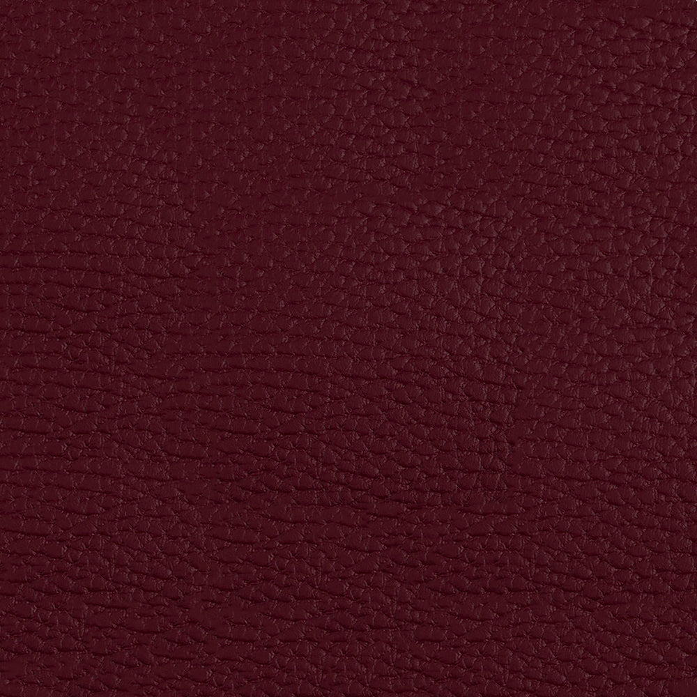 Close-up of burgundy pebbled fabric texture with rich wine red hue.