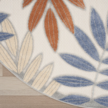 Outdoor round rug with blue and orange leaf patterns on cream background; visible edge.