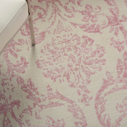 Beige rug with pink damask pattern; partial view of a cream sofa with a silver metal leg.