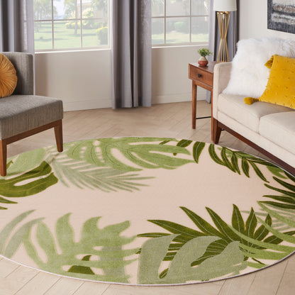 Round beige rug with green tropical leaf pattern in a sunlit, modern living room.