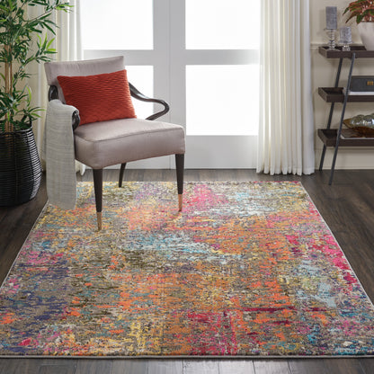 Contemporary living room with a vibrant abstract multicolor rug, beige armchair, red pillow, gray blanket, and plants.