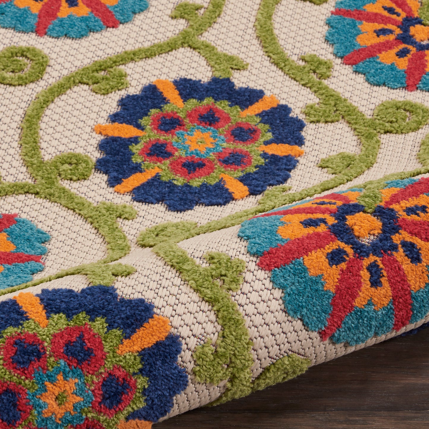 Boho floral tufted area rug with green vines and bright blue, orange, red flowers on beige woven backdrop.