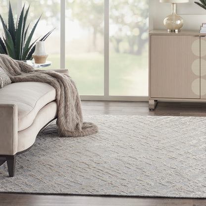 Beige sofa with taupe knit throw, light gray patterned rug, large plant, and light wood cabinet by sunny windows.