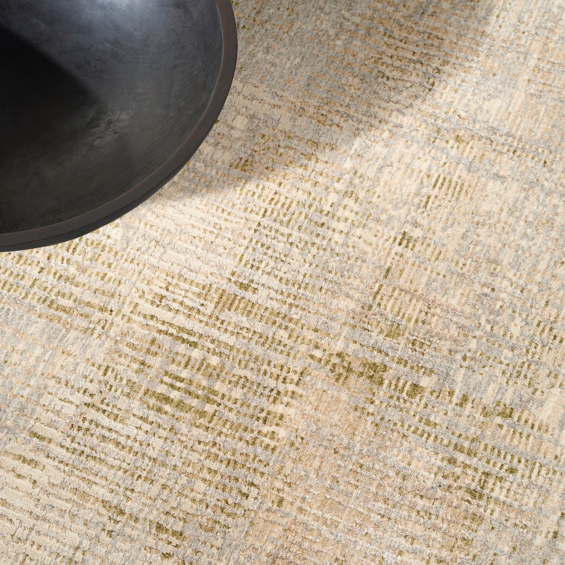 Partial view of a beige textured rug with a subtle pattern in the upper-left corner.