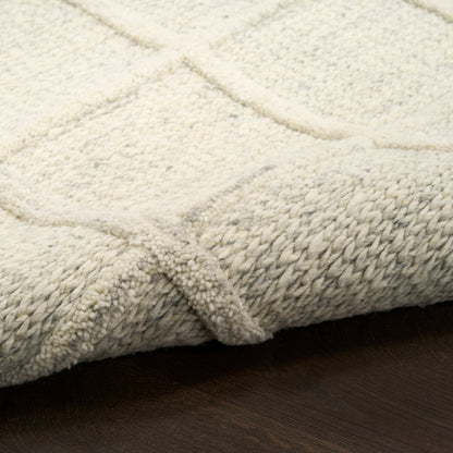 Cream textured area rug with a geometric square pattern; plush looped pile, folded edge on dark wooden floor.