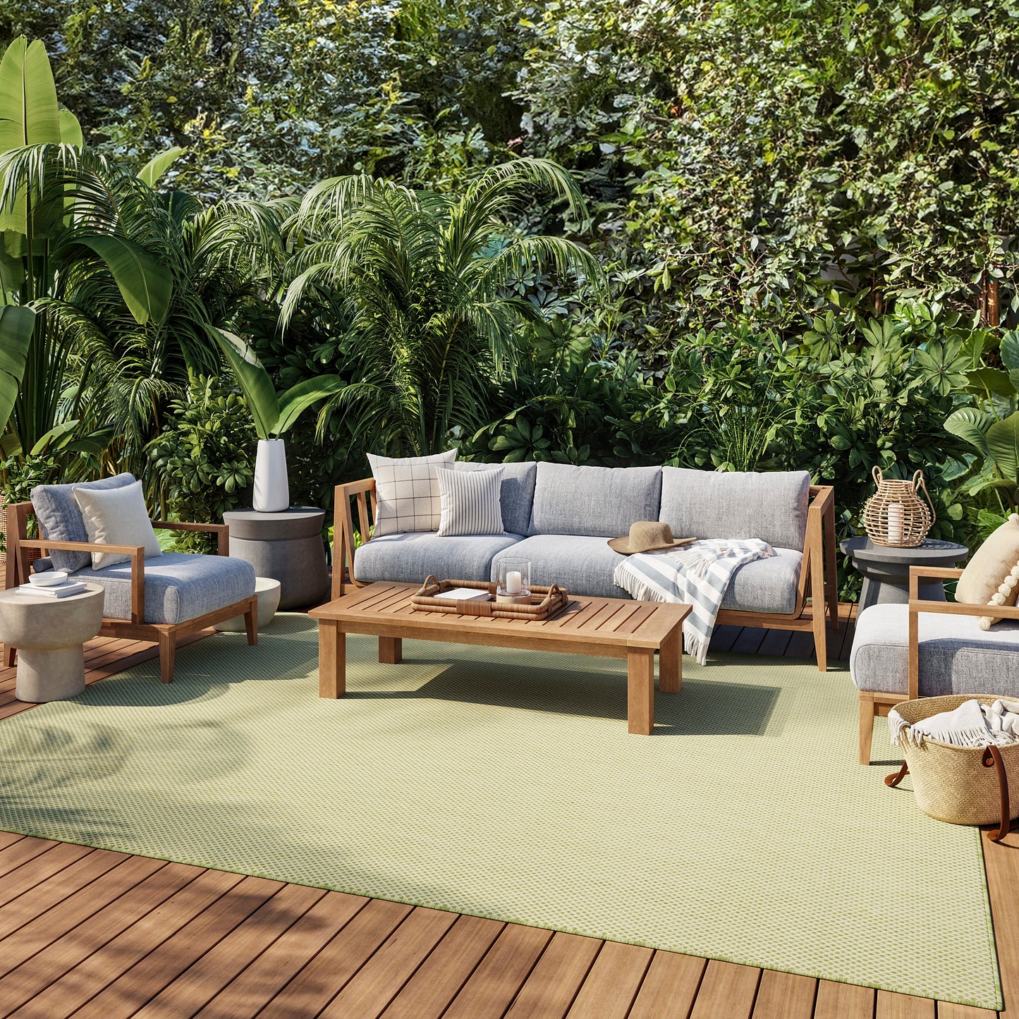Outdoor wooden-frame sofa and chairs with gray cushions, coffee table, beige throw, on a light green rug amid lush greenery.