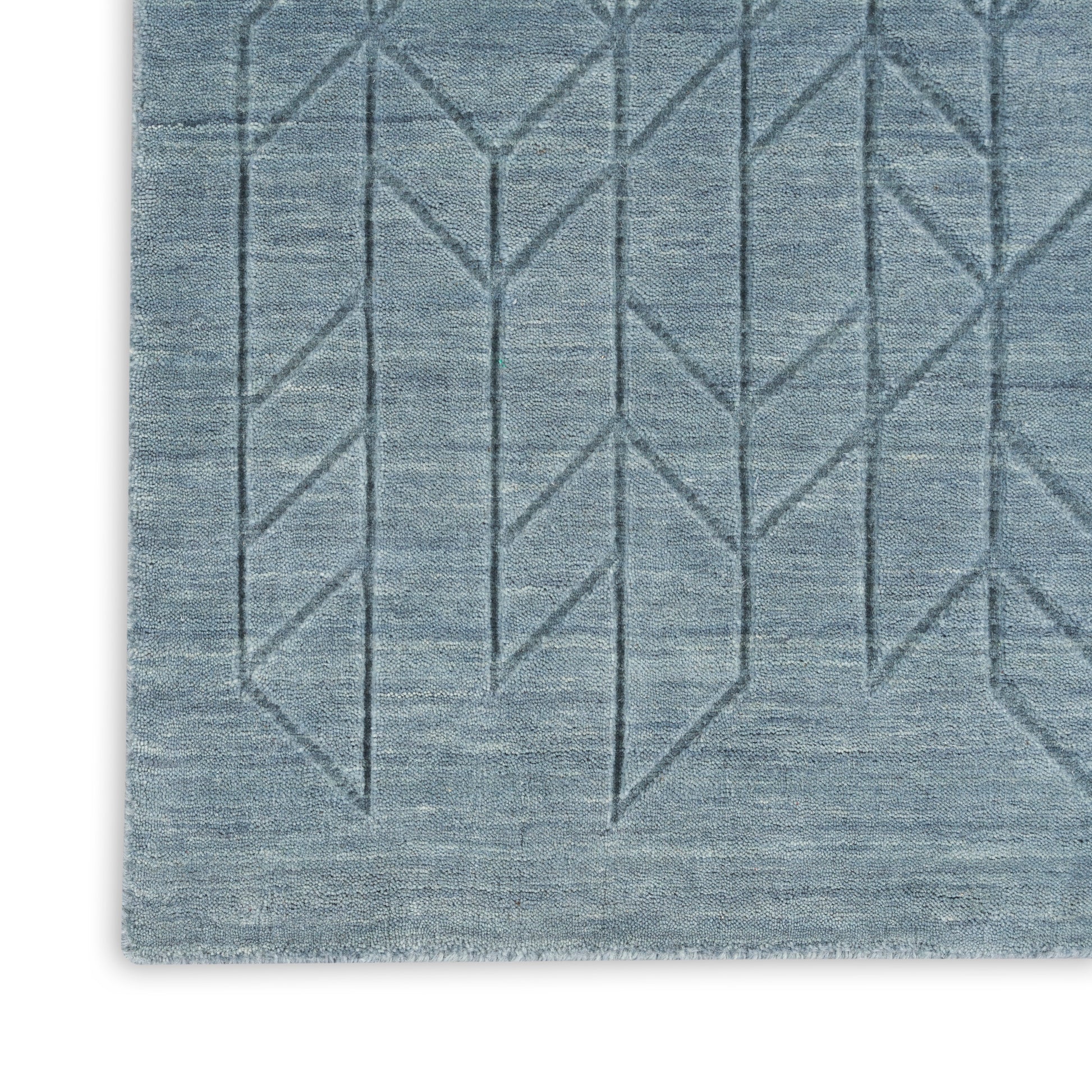 Blue geometric-pattern rug with chevron lines and subtle gradient, woven texture.