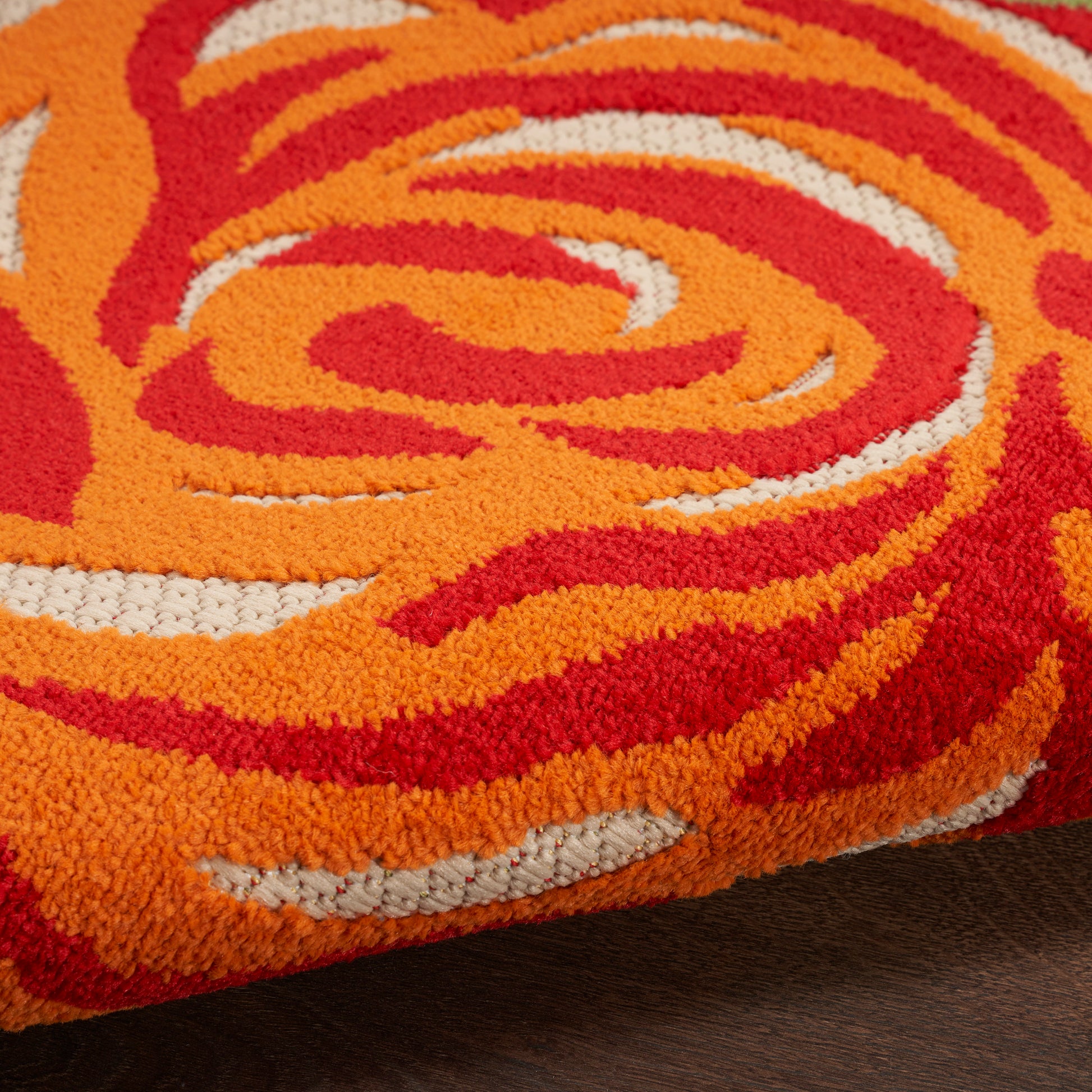 Close-up of a bright orange and red swirling shag rug with white accents.