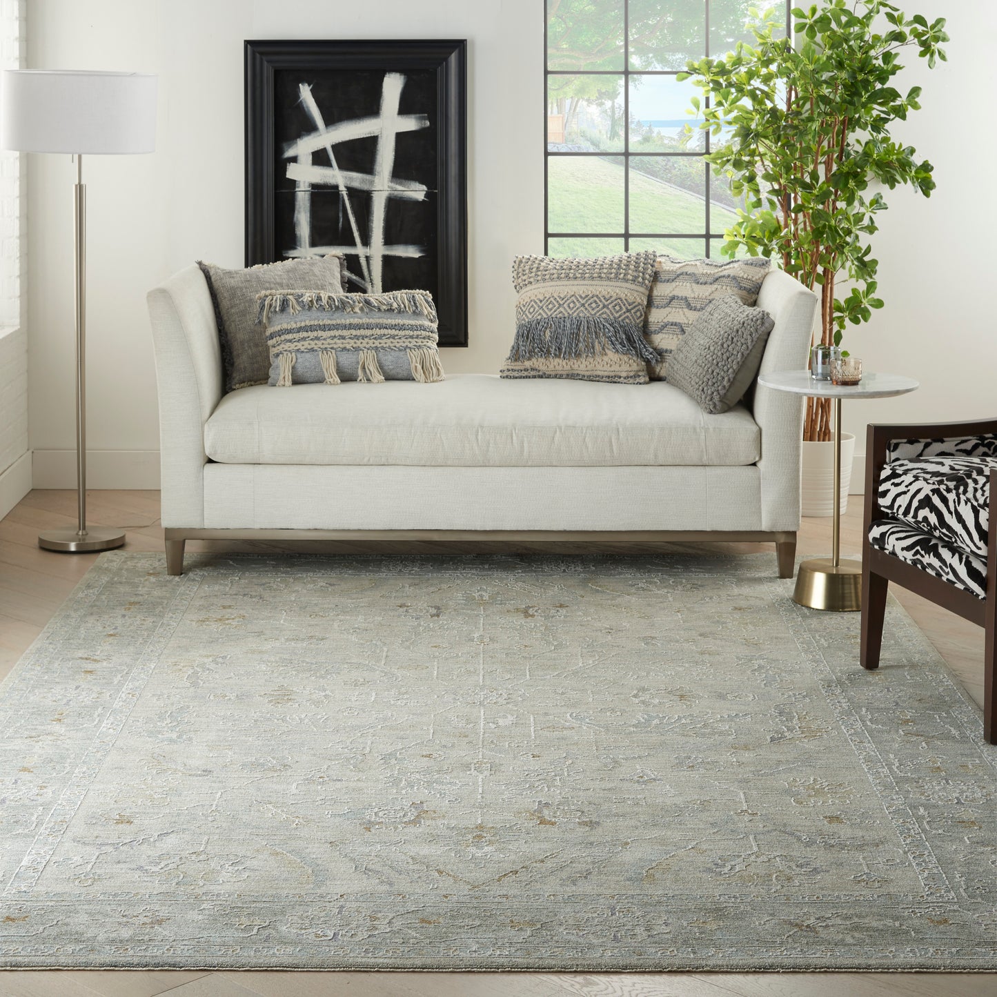 8' x 10' vintage rug in a living room setting with a light gray sofa, textured pillows, large abstract wall art, floor lamp, and plant.