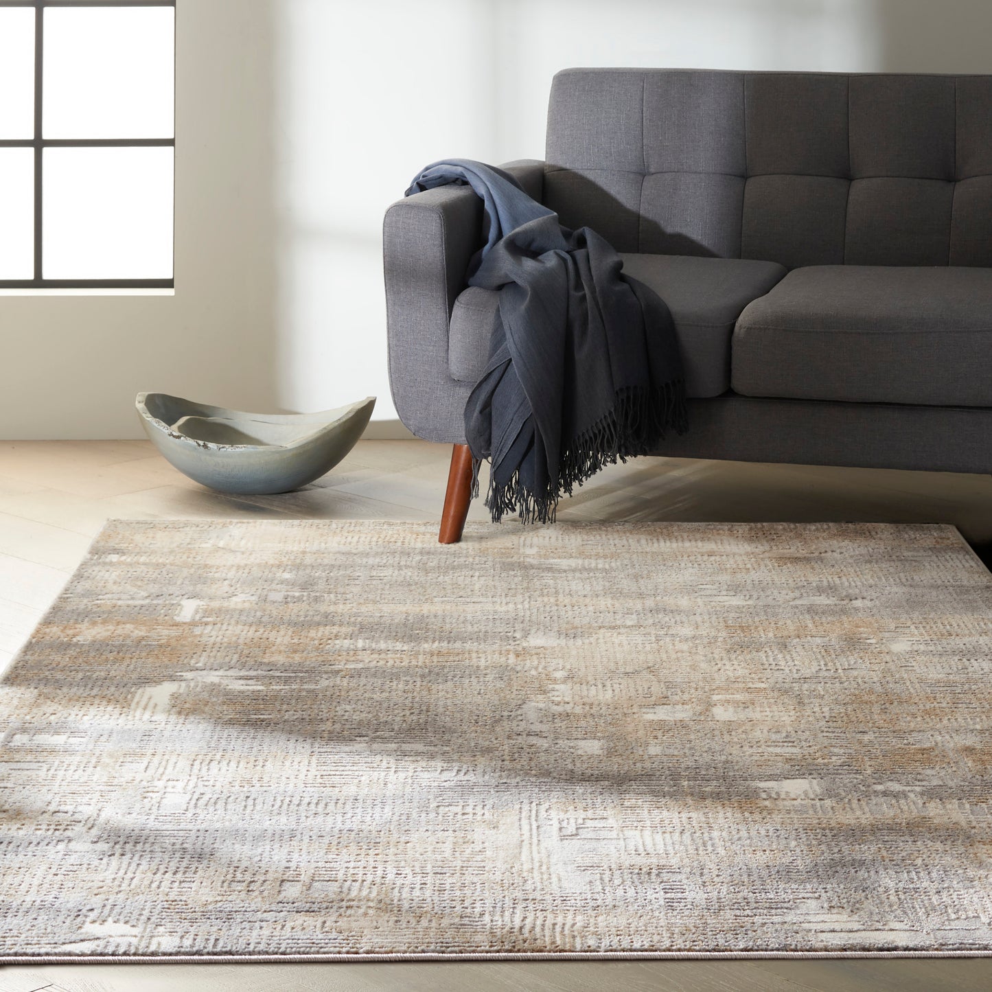 Grey modern rug with a beige pattern on a light wood floor, with a ceramic bowl nearby.