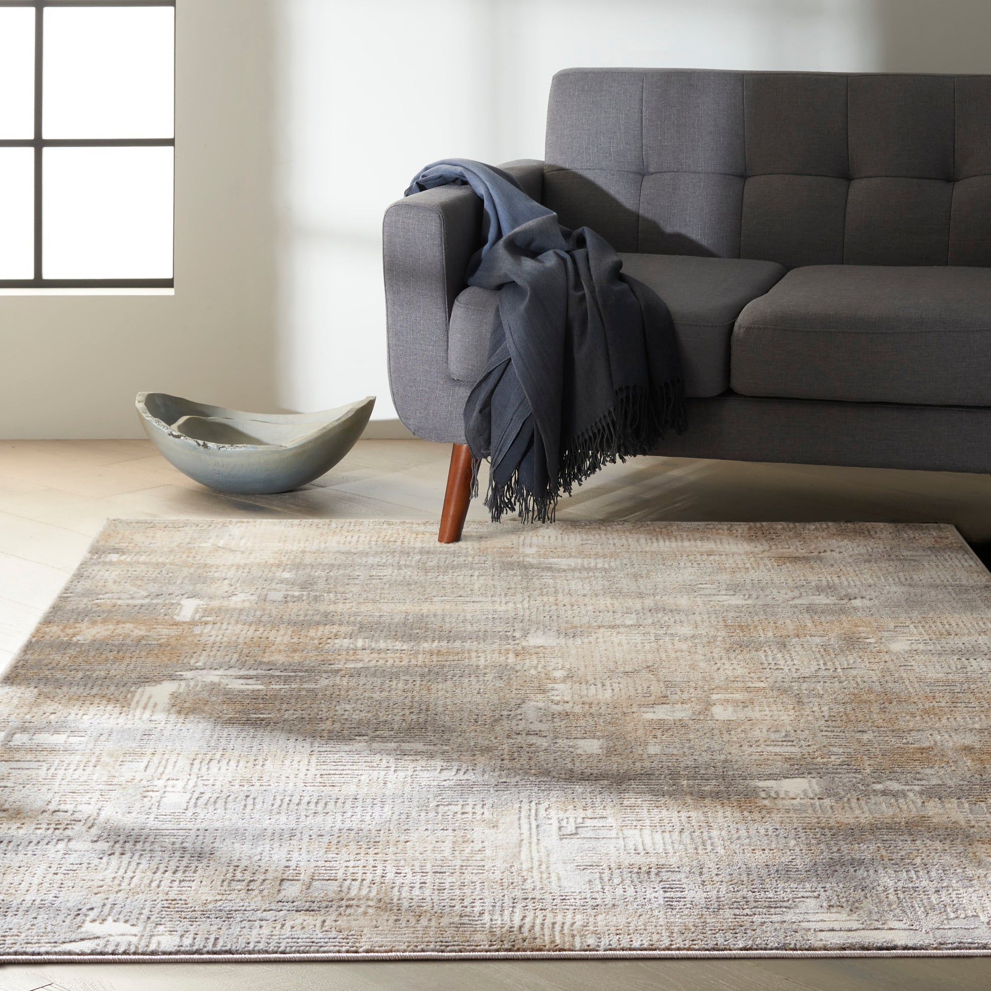 Grey modern rug with a beige pattern on a light wood floor, with a ceramic bowl nearby.