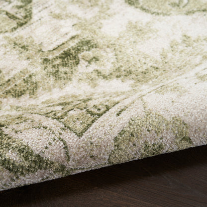 Close-up of sage green and ivory oriental-style rug with plush pile, folded edge on dark wood floor
