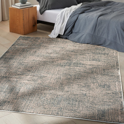 Gray and beige patchwork area rug in a modern bedroom; textured low-pile surface beside a wooden nightstand and dark bedding.