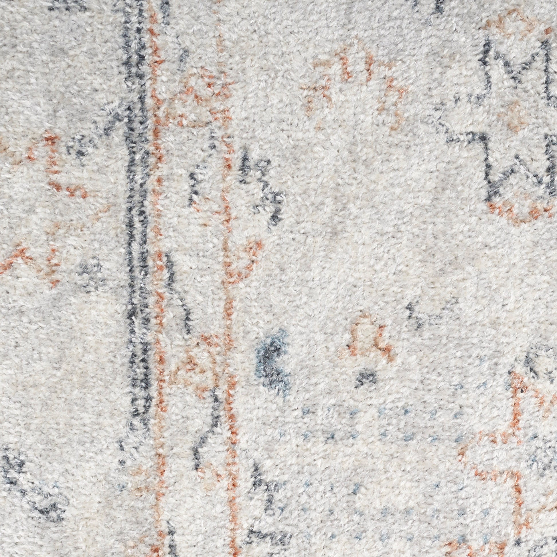 Beige plush rug close-up with blue and orange abstract motifs and a dark vertical line.