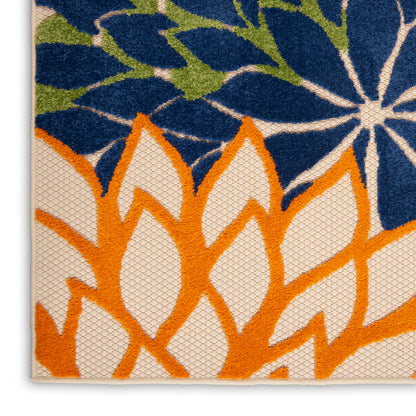 Close-up of a woven rug with bright orange leaf shapes over a cream background & blue floral accents; textured weave.