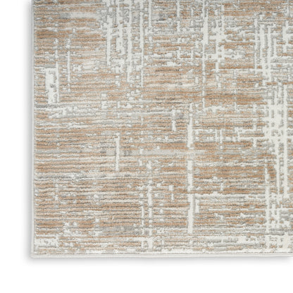 Rectangular beige and taupe area rug with white abstract geometric pattern and plush textured pile.