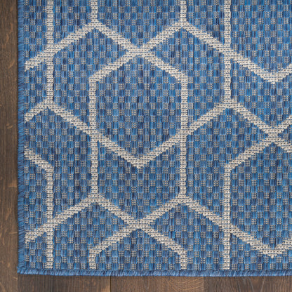 Blue woven area rug with cream beige diamond lattice pattern and textured grid weave on dark wood floor